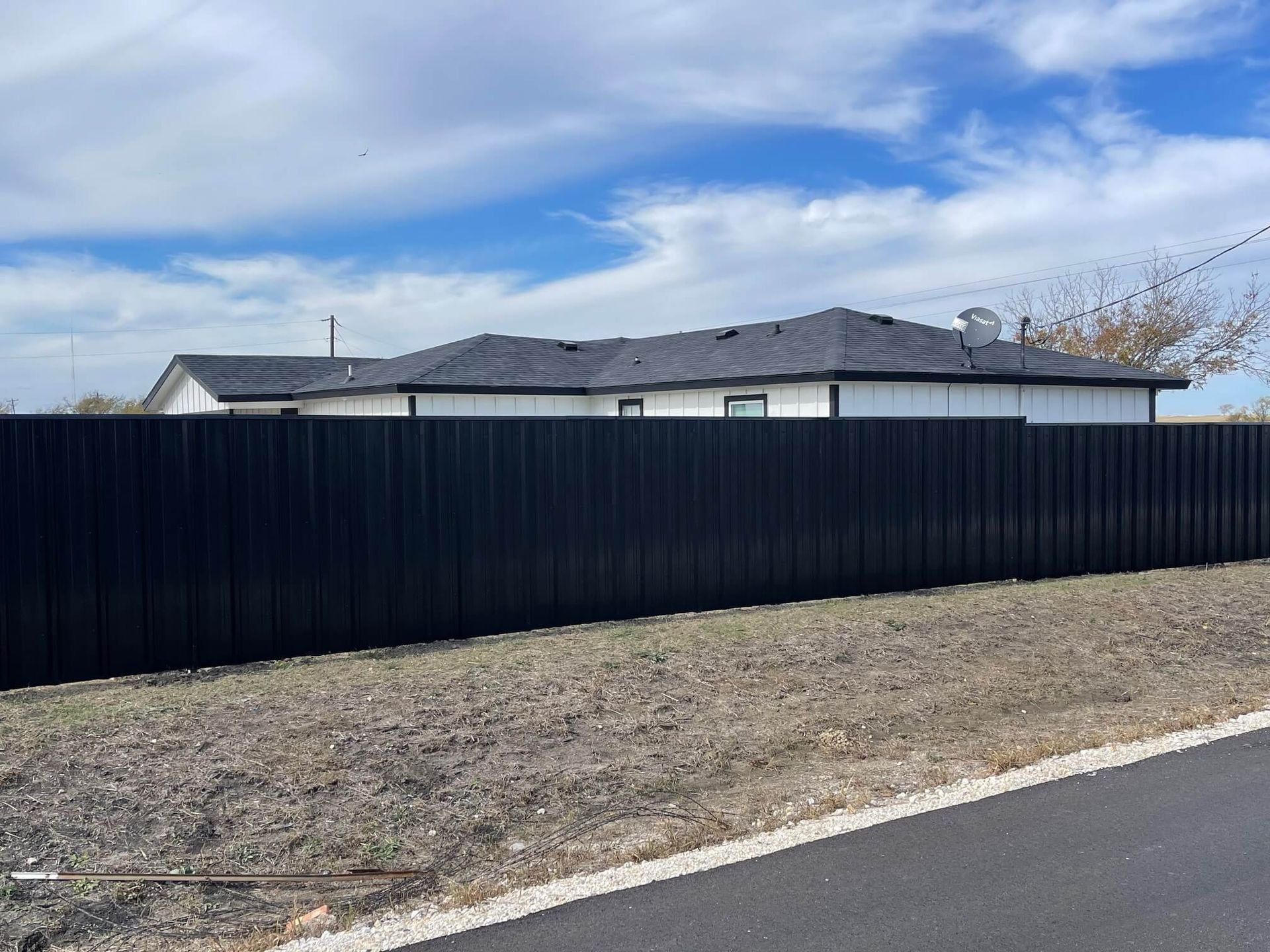 A Black Fence Surrounds a House on The Side of A Road