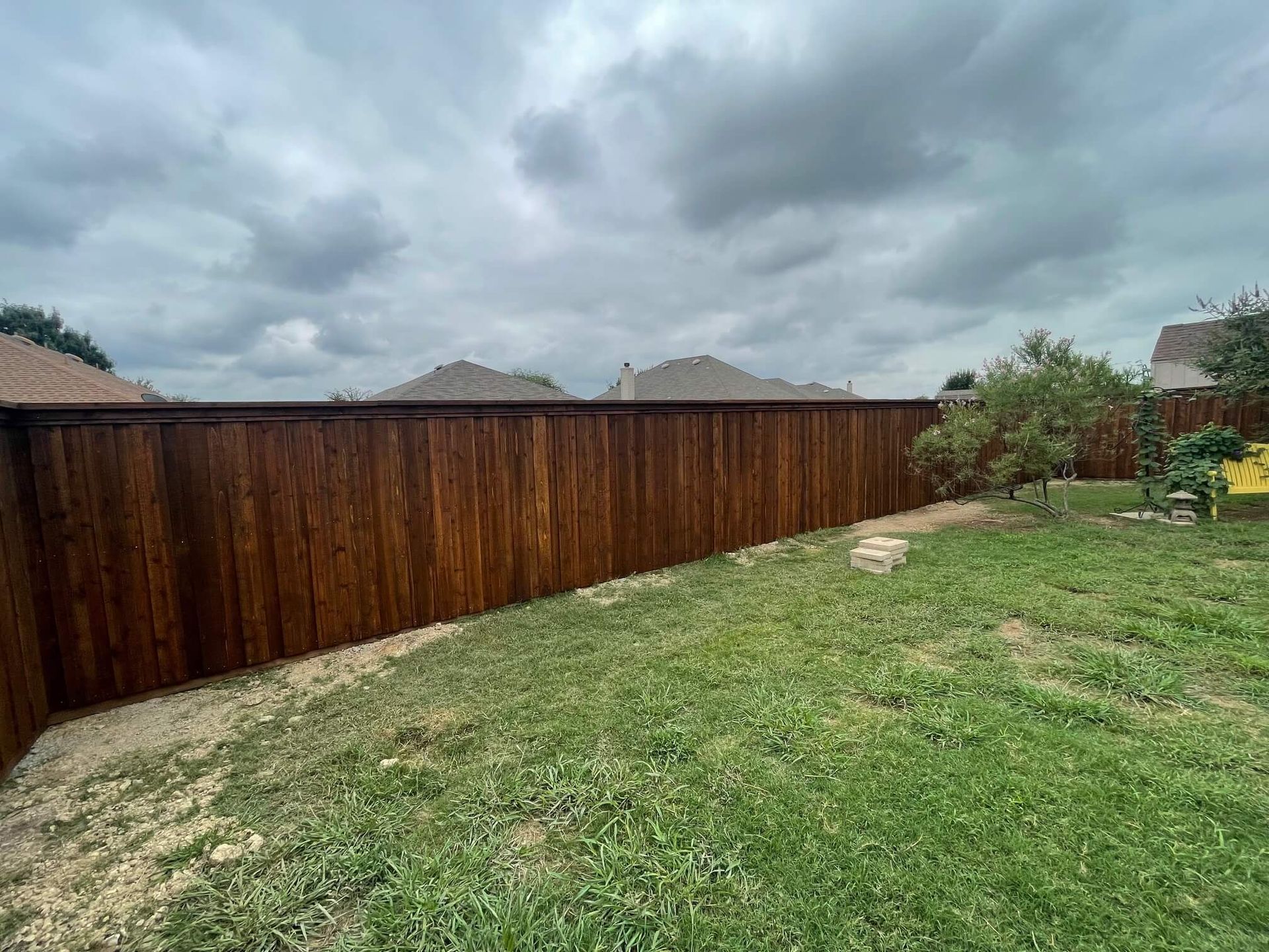 A Wooden Fence Surrounds a Lush Green Lawn in A Backyard