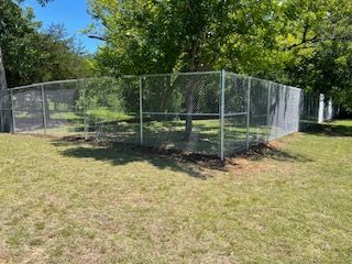 Chain Link Fence Surrounding a Grassy Area in A Park