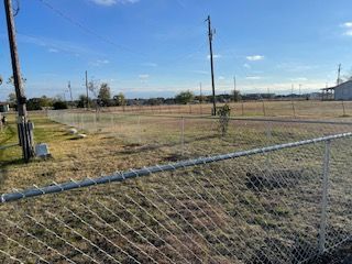Chain Link Fence Surrounds a Large Grassy Field