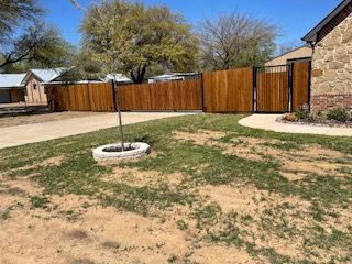 Wooden Fence Surrounds a Yard with A Fire Pit in The Middle of It