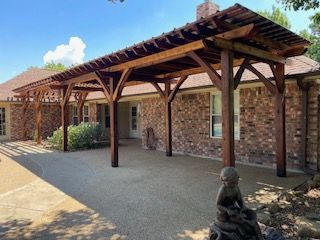 Wooden Pergola Is Sitting in Front of A Brick House