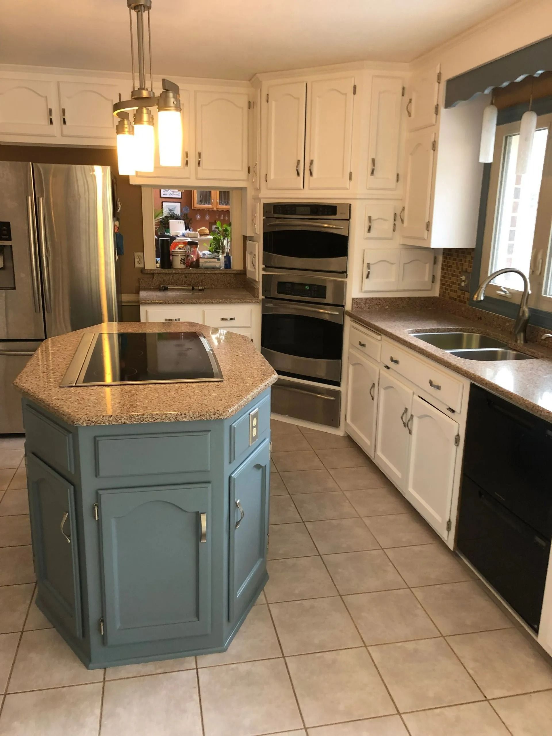 Kitchen with white cabinets, blue island, stainless appliances, and beige countertops.