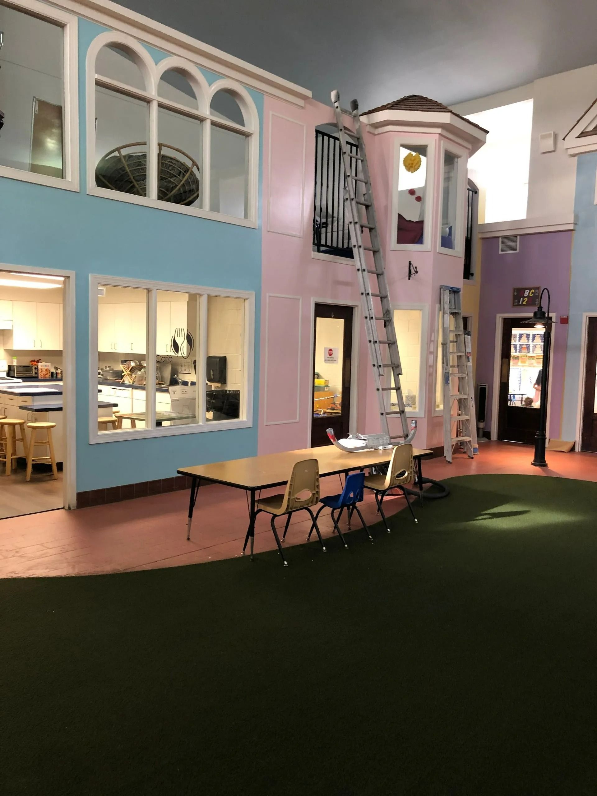 Playhouse interior with colorful walls, tables, chairs, and ladders.