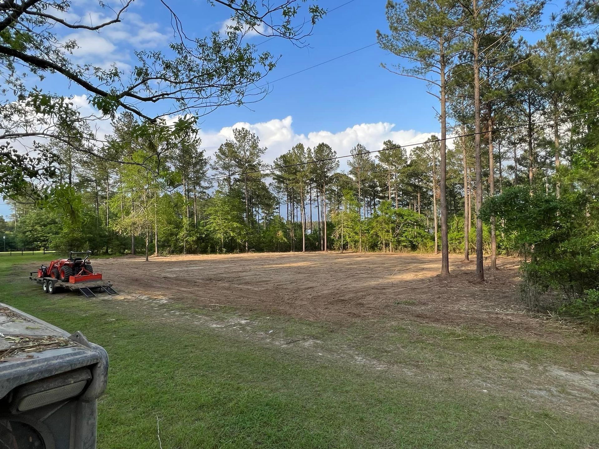 A tractor is sitting in the middle of a field with trees in the background.