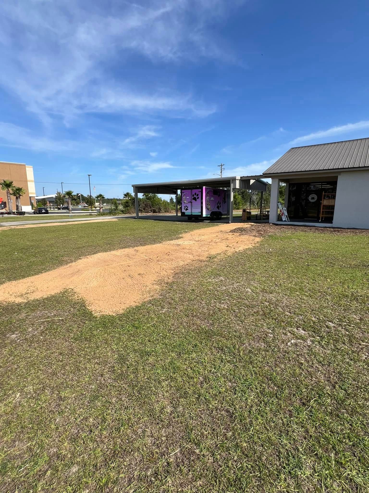 A truck is parked in a grassy field next to a house.