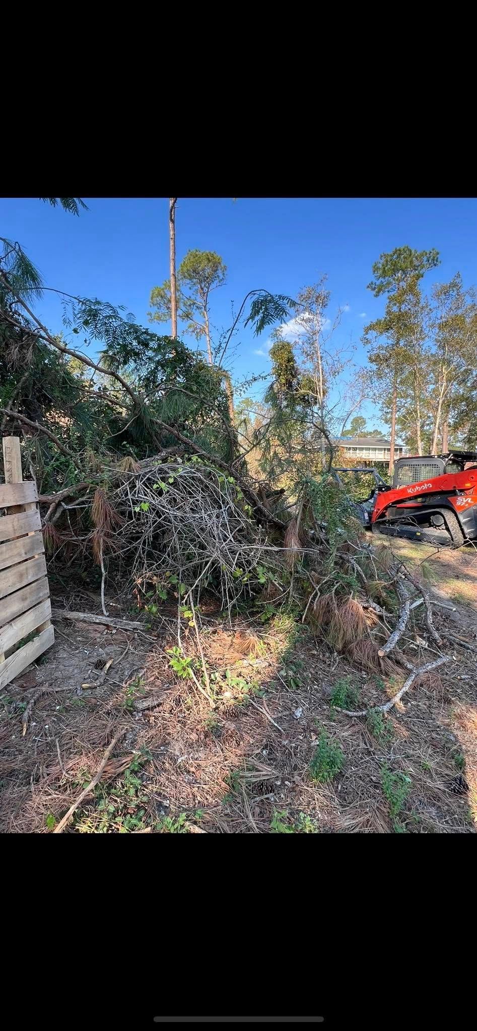 A red atv is parked next to a pile of trees.
