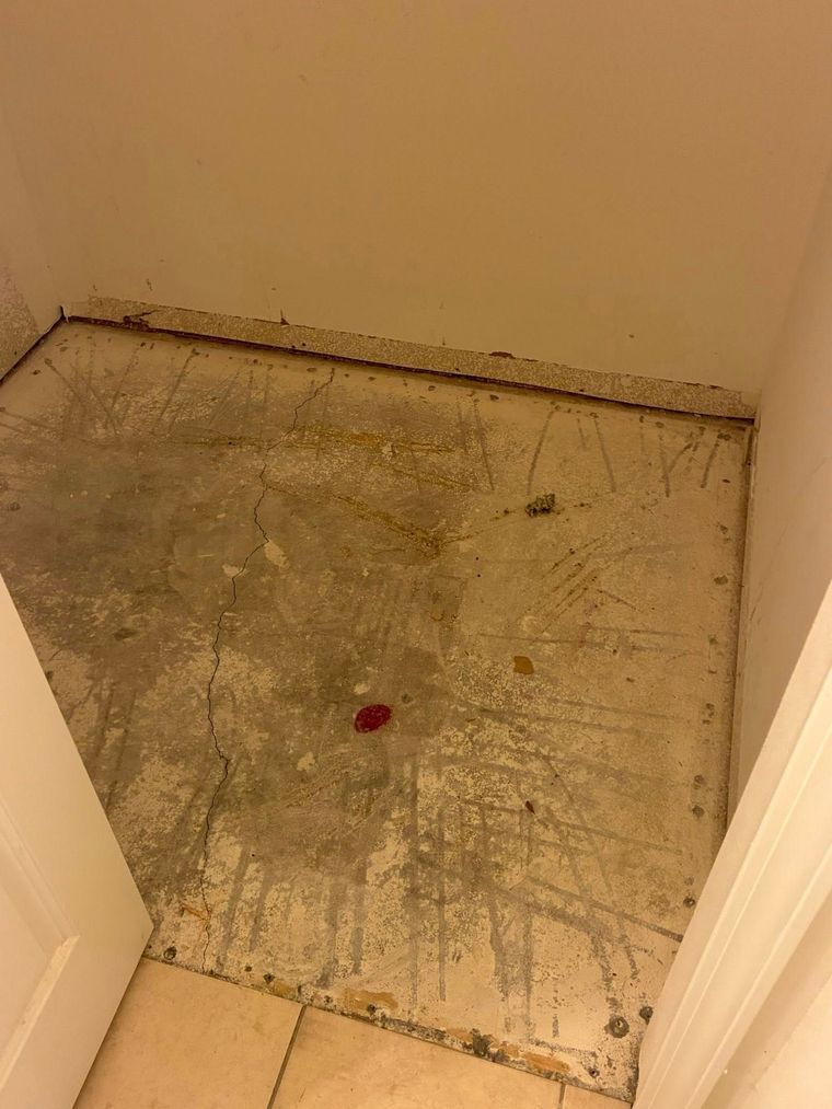 Bare concrete floor in a doorway, with traces of paint and debris. Cream-colored walls and doorframes surround it.