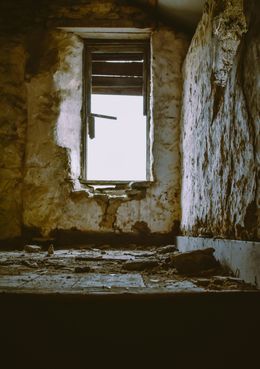 Interior of a dilapidated room. A window with broken shutters looks out. Crumbling walls and debris on the floor.