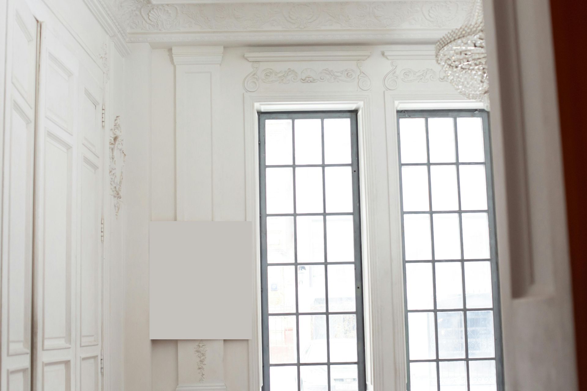 White room with large windows, decorative molding, and a chandelier.