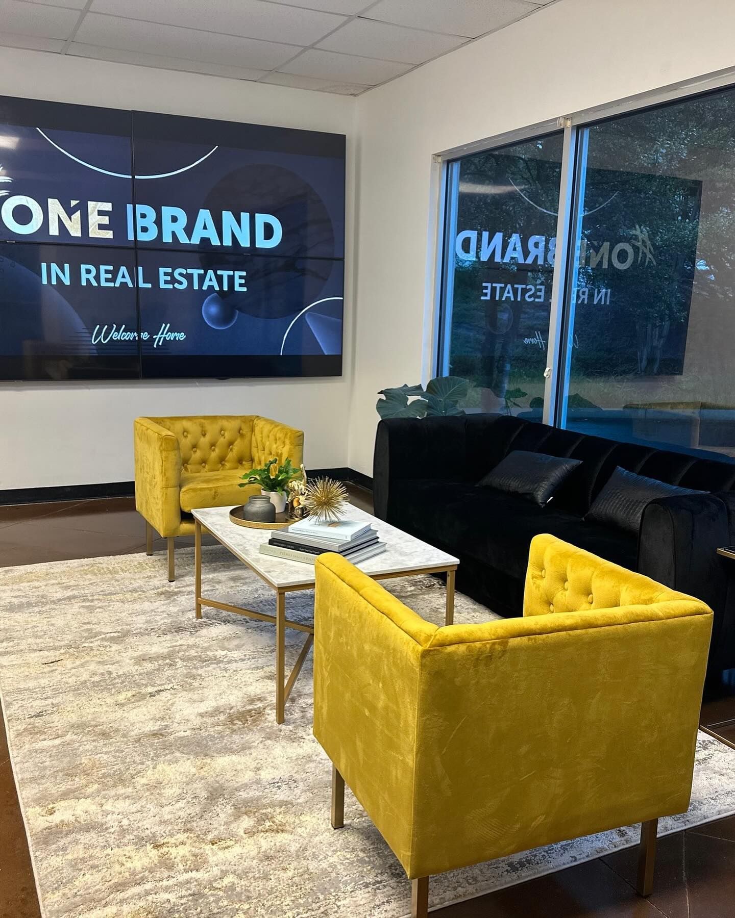 Lounge area: yellow armchairs, black sofa, marble coffee table, rug, and a screen with 