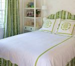 Bedroom with white bedding, green trim, and patterned green headboard and curtains.
