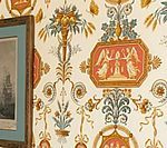 Close-up of ornate wallpaper with a repeating pattern of decorative medallions and floral elements in muted colors.