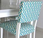 White chair with teal and white geometric patterned cushion and backrest.