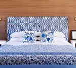 Blue and white patterned bedroom with patterned headboard, pillows, and bedding. Wooden wall behind the bed.