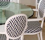 White chairs with black geometric pattern upholstery around a glass table.