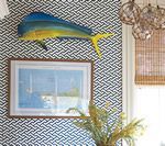 A wall with a blue and yellow fish, nautical chart art, and black and white patterned wallpaper.