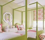 Two twin beds with green canopy frames in a bedroom with patterned green wallpaper and floral accents.