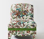Chair upholstered in floral fabric with green trim.