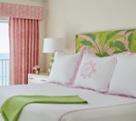 Bedroom with a white bed, pink curtains, green accents, and a tropical-patterned headboard.