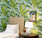 Bedroom with green leaf wallpaper, bed with white bedding, and a nightstand with a lamp.