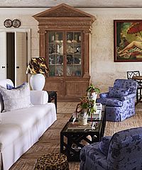 Living room with a large wooden cabinet, blue floral armchairs, and a white sofa.