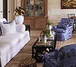 Living room with white sofa, blue floral armchairs, coffee table, and wood cabinet.