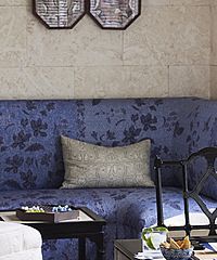 Blue floral couch with tan pillow and wall art above.