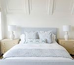 Bedroom with a light blue bed, white bedding, nightstands, lamps, and architectural wall detailing.