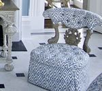 Tufted ottoman and chair in blue and white geometric pattern in a room with a fireplace.