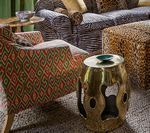 Living room with patterned furniture: zebra-striped sofa, geometric chair, leopard ottoman, brass garden stool.