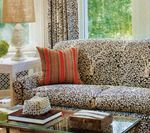 Living room with patterned sofa, red-striped pillow, and a table with a lamp.