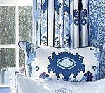 Blue and white patterned throw pillow and curtains in front of a window.