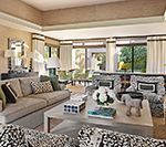 Elegant living room with neutral colors, patterned armchairs, and a view of a lush outdoor space.
