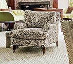 Armchair with patterned fabric in a living room; fireplace and other furniture visible.