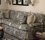 Living room with patterned sofa, neutral pillows, and black and white striped rug.
