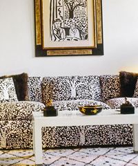Living room with patterned sofa, tree print, white coffee table, and area rug.