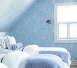 Blue bedroom with patterned wallpaper, white bedding, and a window.