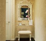 Hallway with patterned wallpaper, ornate mirror, white stool, and closet door.