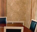 Dining room with wooden table, blue chairs, and textured beige wall. Curtains frame the scene.