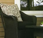 Black wicker armchair with patterned pillow, next to a small table.