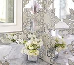 White flowers in silver vases on a marble countertop with a decorative screen and window.