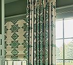 Green and cream patterned curtains and Roman shade in a bright room.