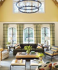 Living room with green patterned curtains, dark sofa, and large chandelier.