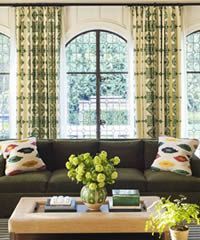 Living room with a dark green couch, patterned curtains, and a coffee table with decor.