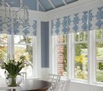 Sunroom with blue patterned valances, white trim, and a round table with flowers.