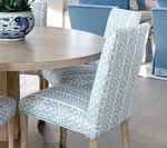 Round wooden table with patterned upholstered chairs in a light-colored room.