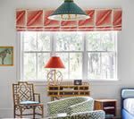 Window with coral Roman shade, turquoise lampshade, and a red table lamp.
