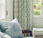 Blue patterned pillows and curtains by a window.