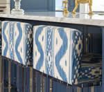 Two blue and white patterned kitchen bar stools under a blue counter.